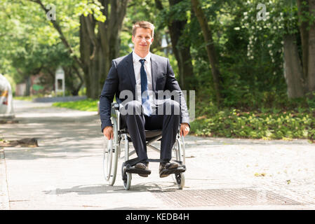 Ritratto di giovane felice uomo disabili su sedia a rotelle Foto Stock