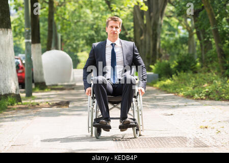 Ritratto di giovane felice uomo disabili su sedia a rotelle Foto Stock