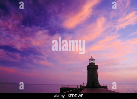 Guernsey. Porto di San Pietro. Frangiflutti del castello e faro all'alba. Foto Stock