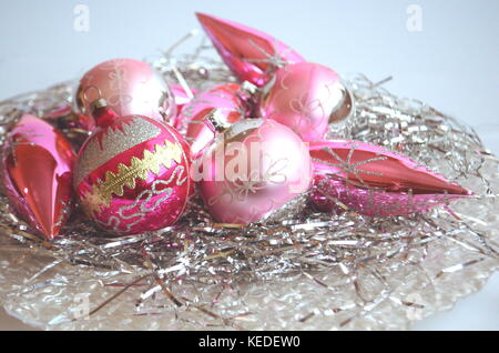 Rosa smerigliato palle di Natale e baubles su un nido di capelli di argento in una madre-di-pera piastra con spazio di copia Foto Stock