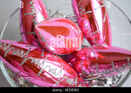 Rosa smerigliato palle di Natale e baubles su un nido di capelli di argento in una madre-di-pera piastra con spazio di copia Foto Stock