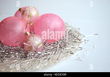 Rosa smerigliato palle di Natale e baubles su un nido di capelli di argento in una madre-di-pera piastra con spazio di copia Foto Stock