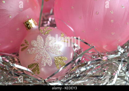 Rosa smerigliato palle di Natale e baubles su un nido di capelli di argento in una madre-di-pera piastra con spazio di copia Foto Stock