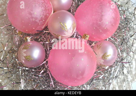 Fatti a mano di colore rosa smerigliato palle di Natale e baubles su un nido di capelli di argento in una madre-di-pera piastra con copia spazio. Schema piatto. Foto Stock