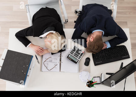 Stanco di due giovani imprenditori di dormire sulla scrivania in ufficio Foto Stock