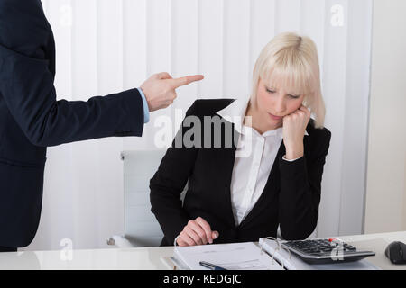 Foto di un uomo bullismo giovane imprenditrice in office Foto Stock