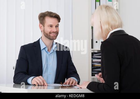 Due giovani imprenditori aventi la conversazione in ufficio Foto Stock