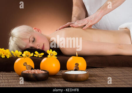 Sorridente giovane donna ricevere massaggio della spalla da un dispositivo massaggiatore in un centro di bellezza e benessere Foto Stock