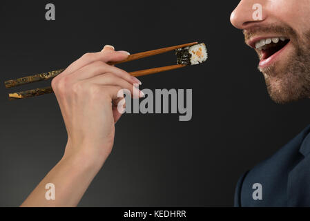 Close-up di alimentazione donna giovane uomo presso un ristorante con sfondo nero Foto Stock