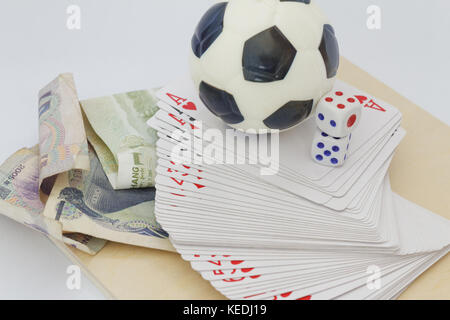 Mini soccer ball sulla parte superiore delle carte da gioco con dadi e denaro in valuta diversa. concetto di scommesse e gioco d'azzardo. Foto Stock