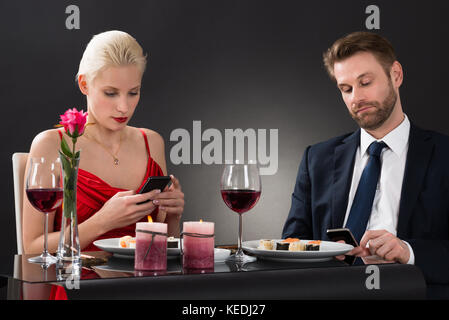 Giovane guardando il loro smartphone in un ristorante Foto Stock