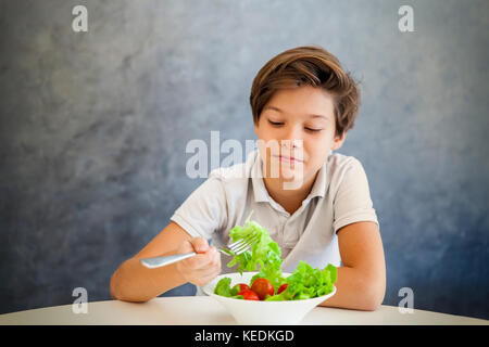 Ritratto di teen boy si rifiuta di mangiare insalata Foto Stock