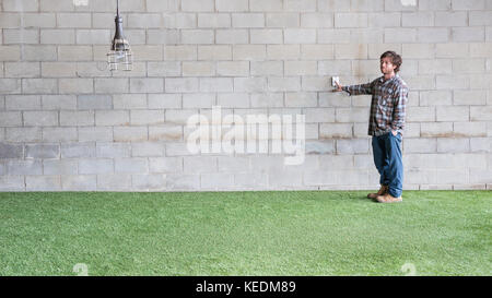 L'uomo toccando un interruttore e spegnendo la lampada a risparmio energetico per promuovere il concetto di ambiente di 'reduce' Foto Stock