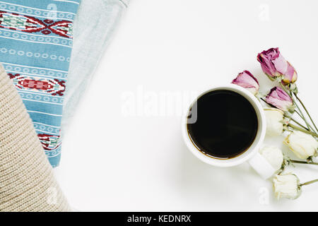 Tazza di caffè e secco rose fiori e abbigliamento vintage isolati su sfondo bianco. vista superiore Foto Stock