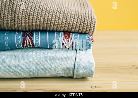 Pila di abiti colorati su un tavolo di legno Foto Stock