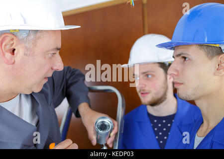 Insegnante osservando gli studenti al lavoro su circuiti elettrici Foto Stock