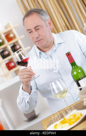 Uomo maturo di bere un bicchiere di vino rosso a casa Foto Stock