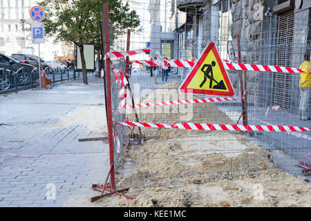 I lavori di riparazione nel centro della zona pedonale in una grande città. sabbia è versato sul marciapiede e recintata con un nastro protettivo. Foto Stock