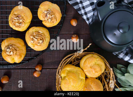 Profiterole aria riempito con crema al caramello con dadi, teiera sul legno scuro dello sfondo. vista dall'alto. Foto Stock