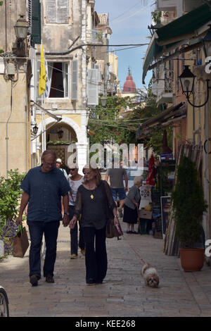 Un paio di camminare lungo una strada stretta con il loro cane al guinzaglio nella città vecchia di kerkira su corfu nelle isole greche. Foto Stock