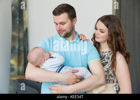 Felice attraente giovane famiglia con bambino sulle mani. Foto Stock