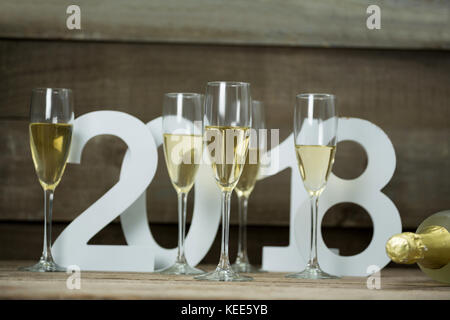 Bicchieri di Champagne circondato contro la formazione di numeri 2018 anno su una superficie in legno Foto Stock