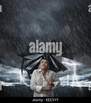 Deluso Uomo con ombrello rotto dopo un inaspettato tempesta, egli è bagnato e il gocciolamento Foto Stock