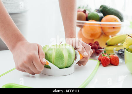 Donna preparare un delizioso snack vegano nella sua cucina con frutta, ella è affettare un organico di mela verde utilizzando una taglierina Foto Stock