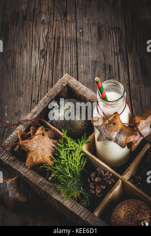 Dolce natalizio e tratta, bottiglia con latte per santa con pan di zenzero star cookies con decorazione corda e decorazioni di Natale, in una scatola di legno, o Foto Stock