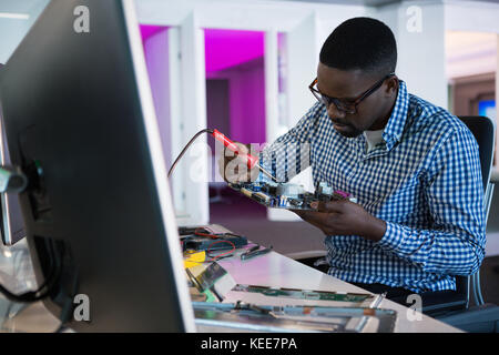 Ingegnere Informatico riparazione scheda madre alla scrivania in ufficio Foto Stock