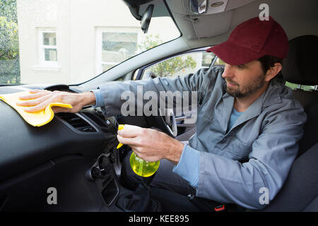 Lavoratore di sesso maschile la spruzzatura di acqua sul cruscotto di automobile Foto Stock