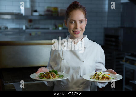 Ritratto di donna chef tenendo la piastra alimentare Foto Stock