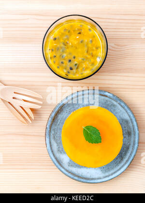 Frutti della passione cheesecake con foglie di menta fresca su sfondo di legno. frutto della passione setup cheesecake con succo di frutto della passione e freschi frutti della passione Foto Stock