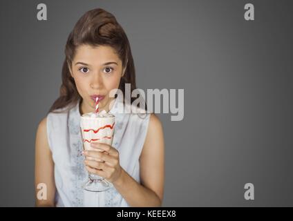 Digital composito della giovane donna contro uno sfondo grigio con crema bevanda dolce Foto Stock