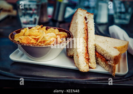 Un burro di arachidi e gelatina sandwich preparati con prodotti freschi di pane bianco e servito con un lato di patatine. oh ya… Foto Stock
