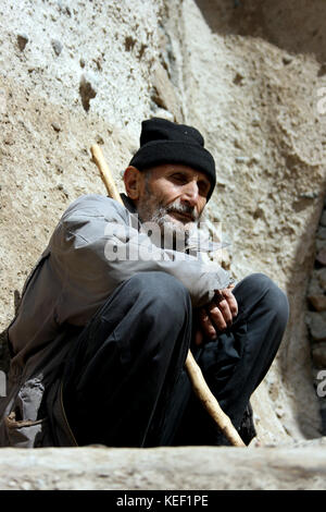 Kandovan, Provincia di Kandovan Azerbaigian, Iran. 8 maggio 2008. Un uomo anziano è visto seduto davanti alla sua casa durante il giorno time.The minuscolo villaggio di Kandovan (aka Kanvan), nella provincia iraniana dell'Azerbaigian orientale è noto per le sue abitazioni di scogliera, non costruito sulle formazioni rocciose, ma scavato nelle rocce vulcaniche stesse. Le formazioni rocciose a forma di cono sono dovute all'erosione dell'acqua della matrice acida porosa, sviluppata dopo l'eruzione del Monte Sahand nel Distretto Centrale della Contea di Osku. Le rocce fungono anche da materiale a basso consumo energetico, mantenendo le case calde in inverno e c Foto Stock