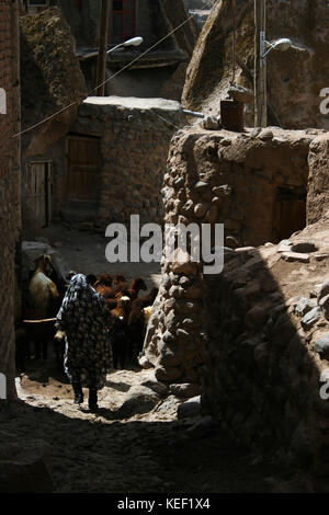 8 maggio 2008 - Kandovan, Provincia di Kandovan Azerbaigian, Iran - UNA donna locale è raffigurata mentre cammina attraverso il vicolo stretto all'interno del villaggio.. Il piccolo villaggio di Kandovan (aka Kanvan), nella provincia dell'Azerbaigian orientale iraniano è conosciuto per le sue abitazioni di scogliera, non costruito sulle formazioni rocciose, ma scolpito nelle rocce vulcaniche stesse. Le formazioni rocciose a forma di cono sono dovute all'erosione dell'acqua della matrice acida porosa, sviluppata dopo l'eruzione del Monte Sahand nel Distretto Centrale della Contea di Osku. Le rocce agiscono anche come un materiale efficiente dal punto di vista energetico, mantenendo le case calde Foto Stock