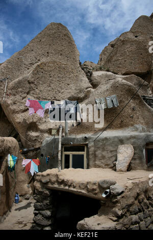 8 maggio 2008 - Kandovan, Provincia di Kandovan Azerbaigian, Iran - vestiti si stanno asciugando fuori di una casa locale.. Il piccolo villaggio di Kandovan (aka Kanvan), nella provincia iraniana dell'Azerbaigian orientale è conosciuto per le sue abitazioni rupestri, non costruite sulle formazioni rocciose, ma scavate nelle rocce vulcaniche stesse. Le formazioni rocciose a forma di cono sono dovute all'erosione dell'acqua della matrice acida porosa, sviluppata dopo l'eruzione del Monte Sahand nel Distretto Centrale della Contea di Osku. Le rocce fungono anche da materiale a basso consumo energetico, mantenendo le case calde in inverno e fresche in estate. A partire da t Foto Stock