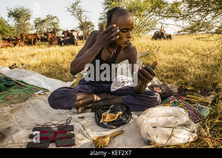 Il Ciad. 28 Sep, 2016. Un wodaabe l uomo si prende una pausa dal tendente al suo bestiame per applicare un po' di make-up per pasta di gerewol. questa tribù nomade ha vagato il Sahel per secoli. Credito: Tariq zaidi/zuma filo/alamy live news Foto Stock