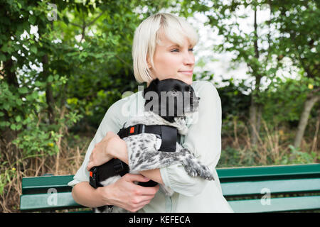 Giovane donna felice abbracciando il suo cane mentre si è seduti sul banco di lavoro Foto Stock