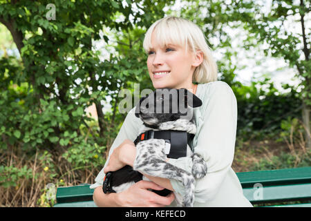 Giovane donna felice abbracciando il suo cane mentre si è seduti sul banco di lavoro Foto Stock