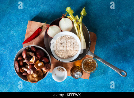 Ingredienti per il risotto con funghi freschi su uno sfondo blu Foto Stock