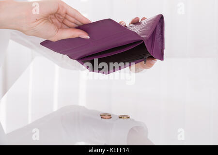 Close-up di donna Holding svuotare il borsellino con monete sulla scrivania Foto Stock