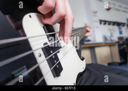 Pupilla in un Regno Unito scuola statale suonare la chitarra basso in lezione di musica Foto Stock