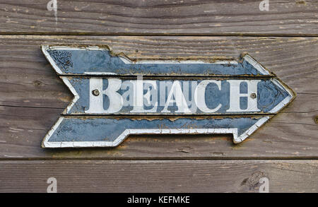 Vintage blu e bianco a forma di orientamento come una freccia dicendo "spiaggia" su pannello in legno parete Foto Stock