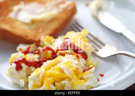 Uova strapazzate con sriracha hot chili e salsa di toast imburrato Foto Stock
