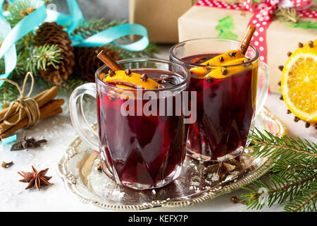 In casa natale cocktail vin brulé vino rosso con bastoncini di cannella, arance e chiodi di garofano, servita in due coppe su una pietra grigio ardesia o. copia di spazio. Foto Stock