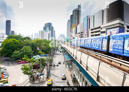 Vista dalla piattaforma della stazione dello skytrain Con il treno che si avvicina attraverso la città di Bangkok Thailandia con la strada trafficata sotto e il Foto Stock