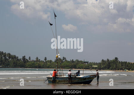 Unawatuna Galle della provincia meridionale dello Sri Lanka pescatori con barca sulla spiaggia Foto Stock