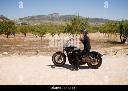 Giovane uomo vestito di nero su un motociclo nero Foto Stock